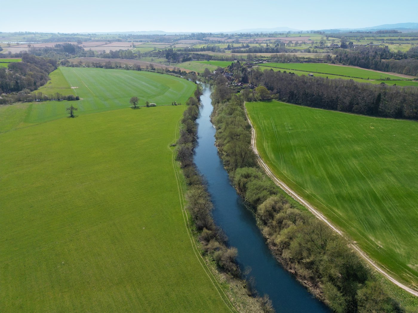 A long, tree-lined reach of the River Severn running between fields near Quatford